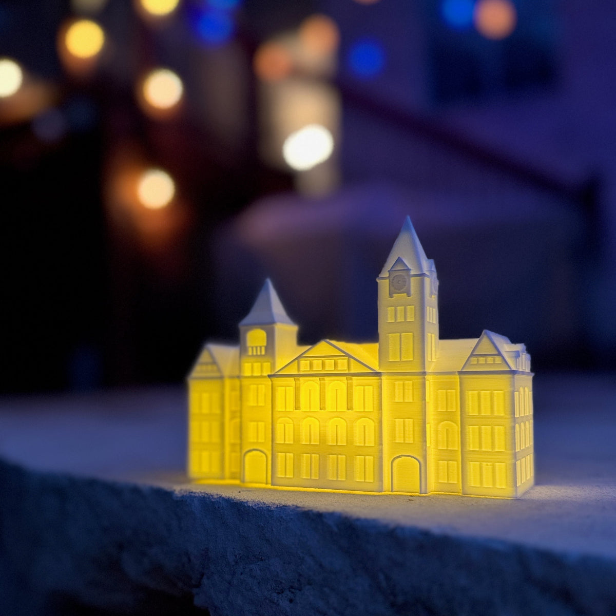 The Auburn Graduation Party figurine (an LED light designed as the Samford Hall building on campus) shown at an outdoor event.