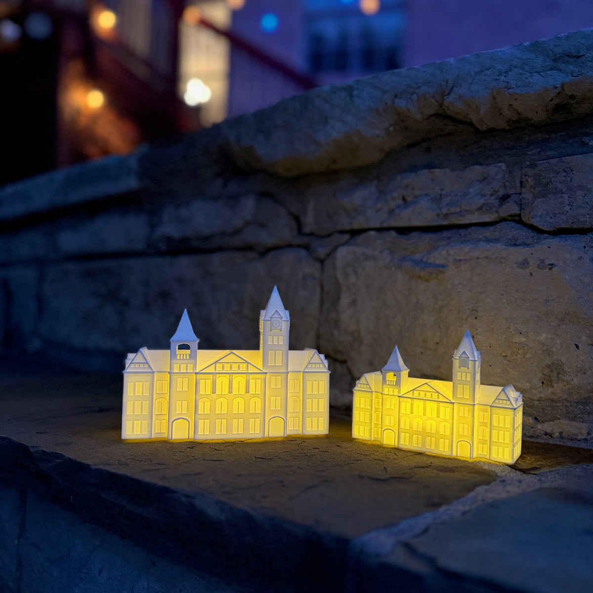 Two Auburn University keepsake figurines (Samford Hall lights) shown at an outdoor wedding with twinkle lights.