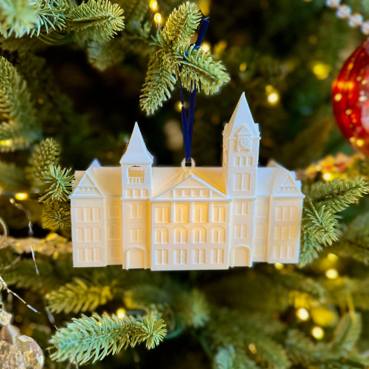 Front view of the LED lighted Samford Hall ornament, shown on an Auburn tree.