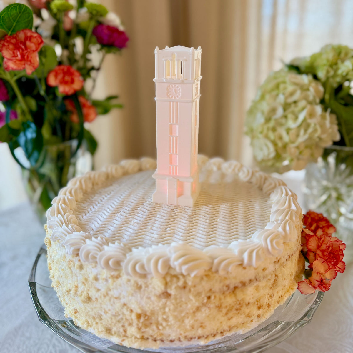 The NC State cake topper figurine depicting the bell tower, and shown on an NC State graduation cake.