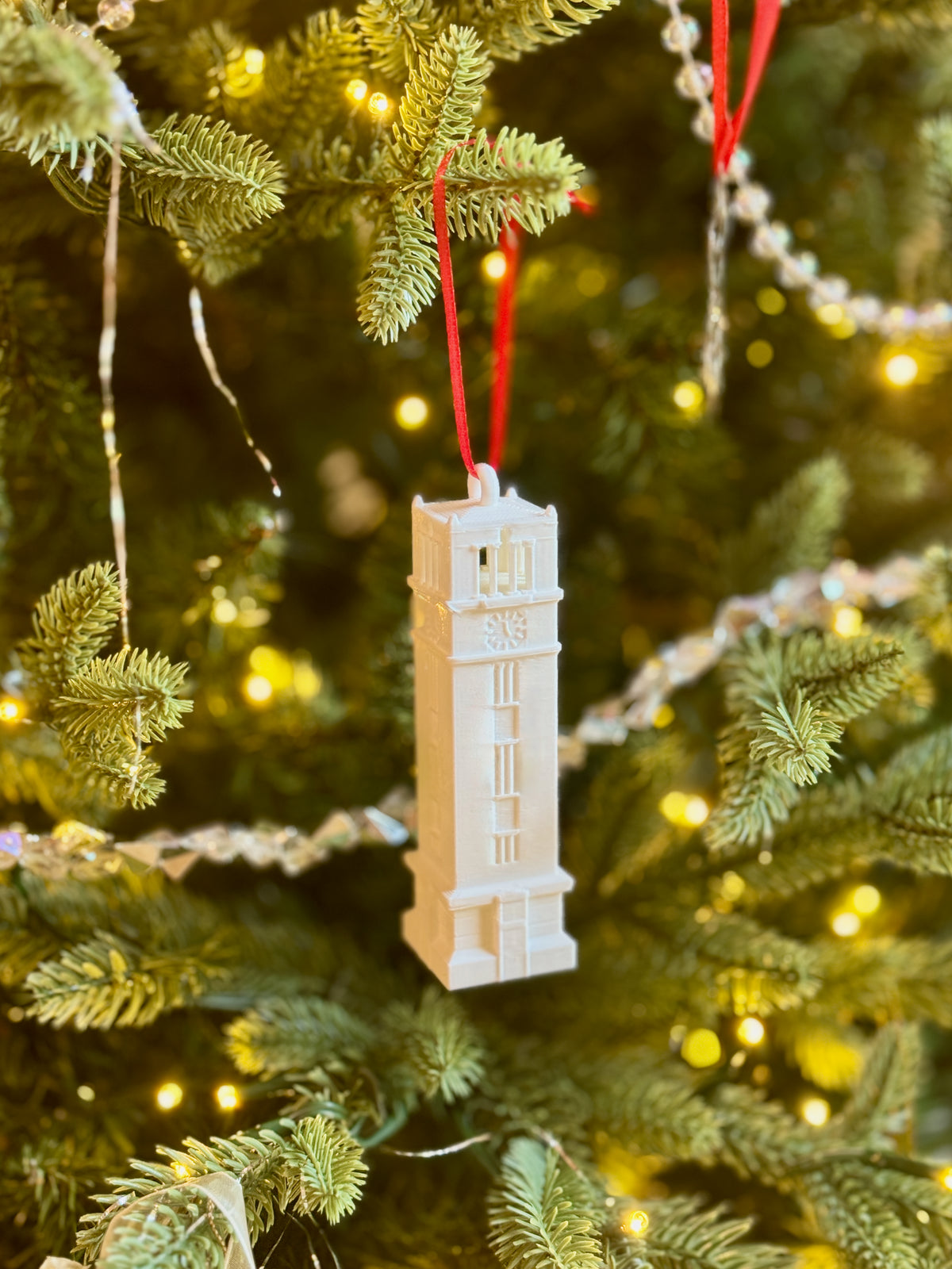 The NC State Wolfpack ornament of the Memorial Bell Tower, shown on a Christmas tree.