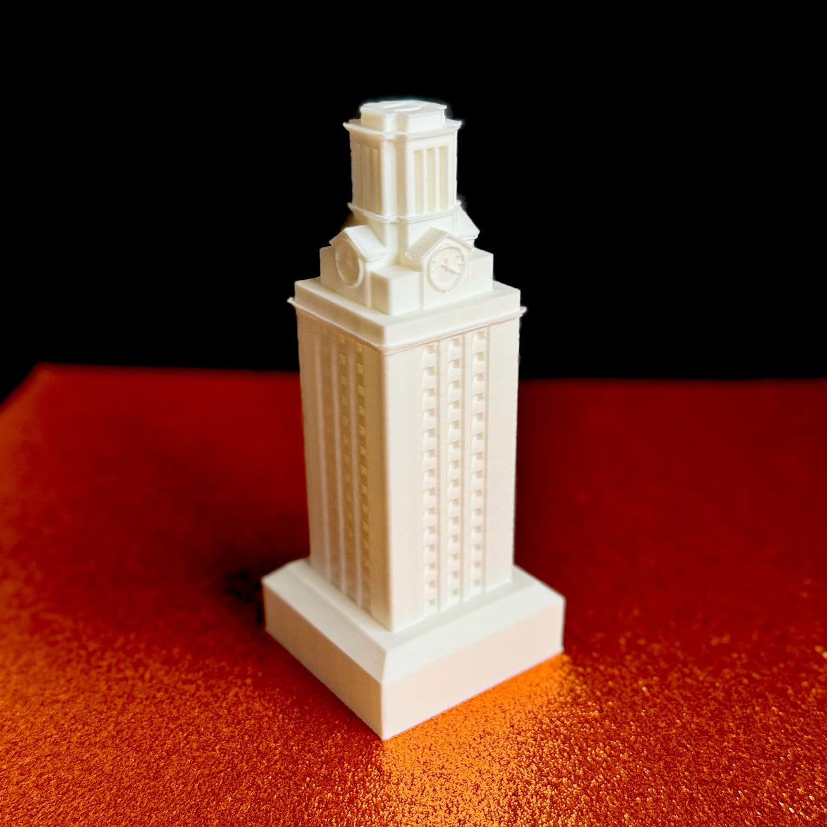 Detailed 3D printed UT Tower model displayed on a burnt orange textured background.