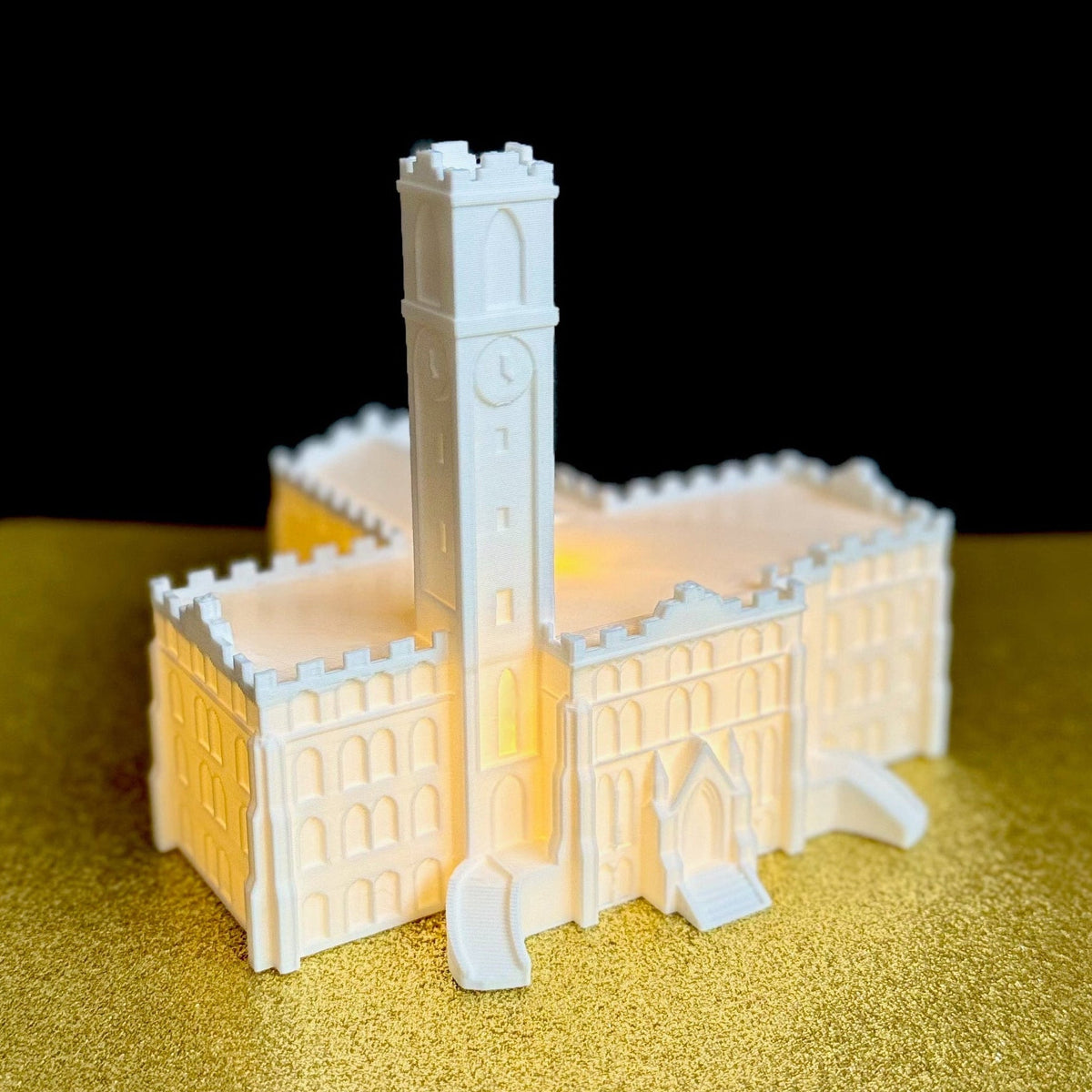 The lighted Vanderbilt University figurine, shown against a gold and black background.