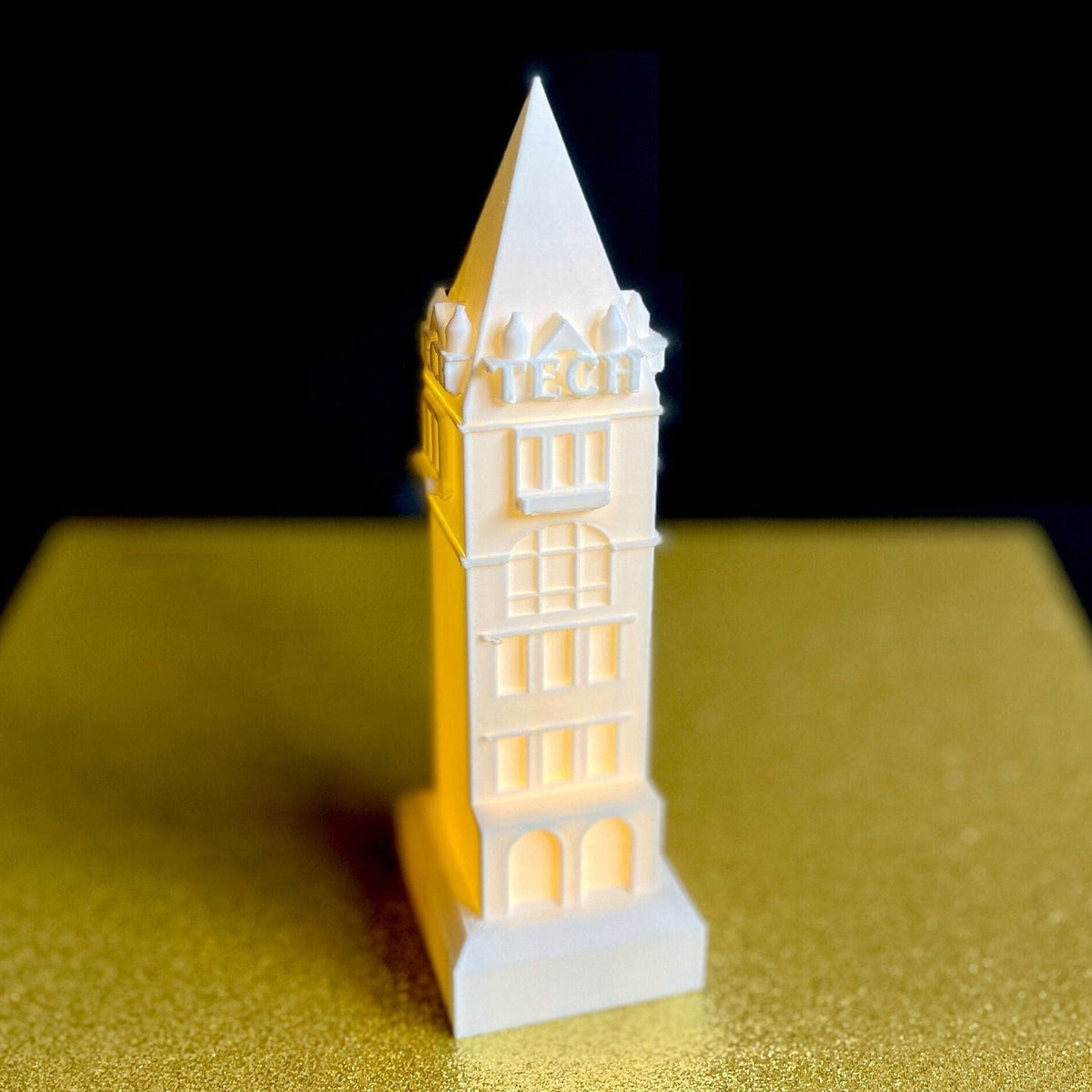 The Georgia Tech lighted figurine representing Tech Tower, shown against a gold background.