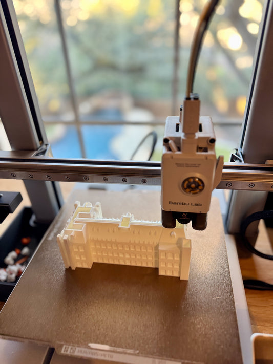 Close-up of 3D printers fabricating components for college landmark figurines with precision and care.