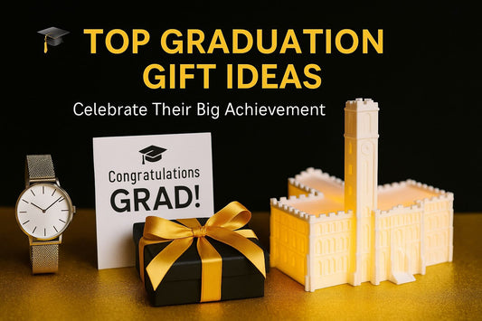 Graduation gift display featuring a glowing Vanderbilt Kirkland Hall LED figurine, a wrapped gift with gold ribbon, a congratulatory card, and a sleek wristwatch on a golden surface.