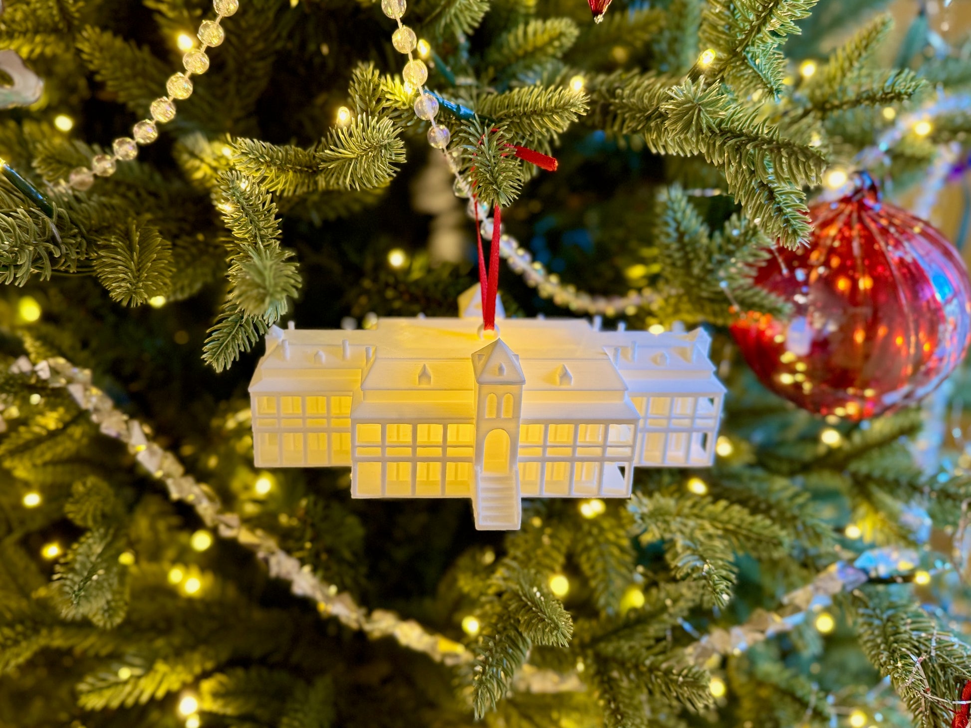Arizona Wildcats ornament of Old Main, shown on a Christmas tree with an LED light.