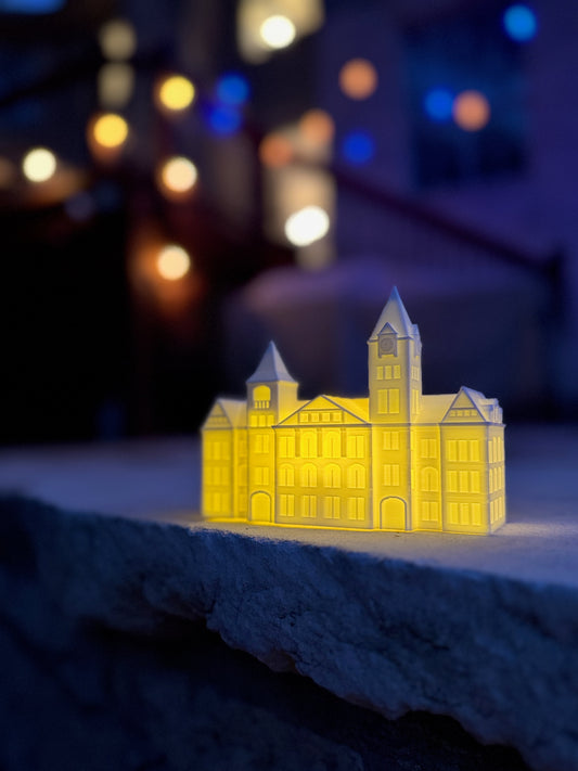 The Auburn Graduation Party figurine (an LED light designed as the Samford Hall building on campus) shown at an outdoor event.