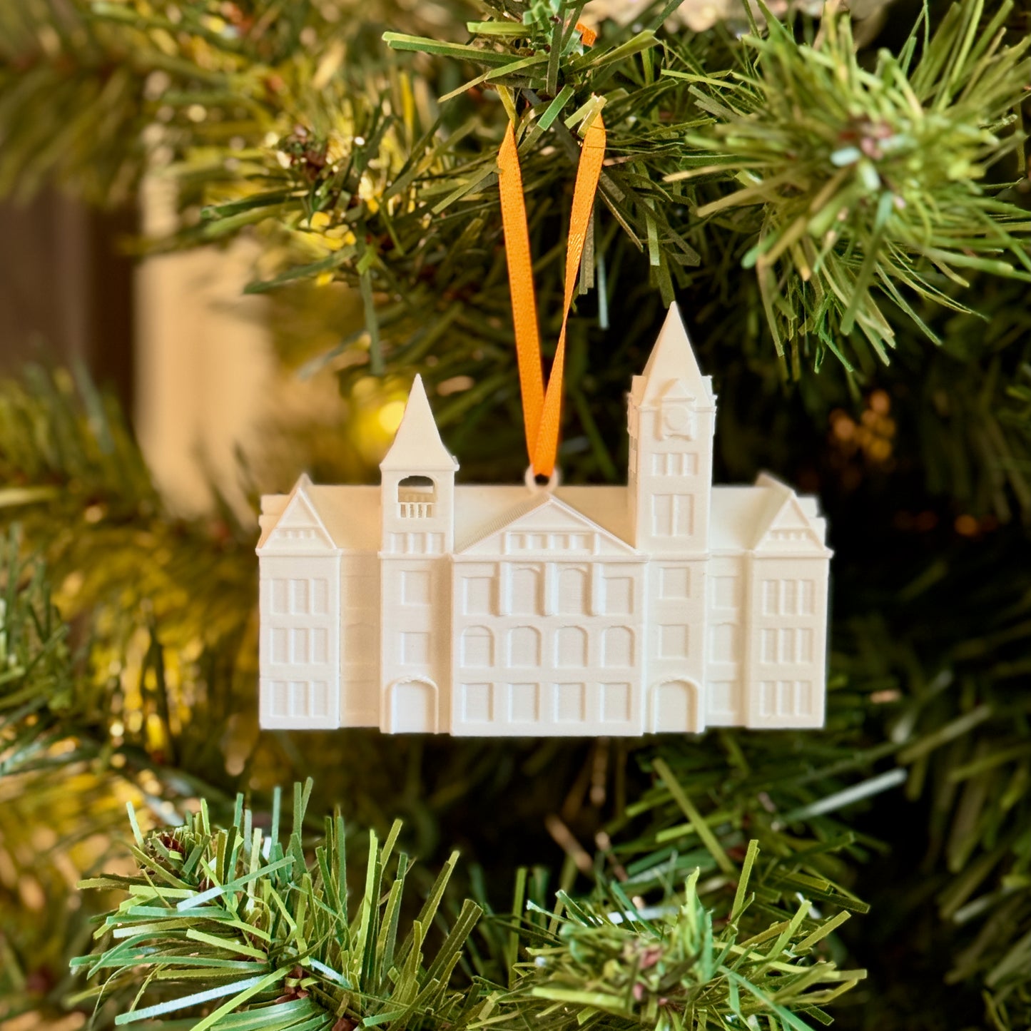 Samford Hall ornament hanging on a lit Christmas tree with traditional holiday decorations