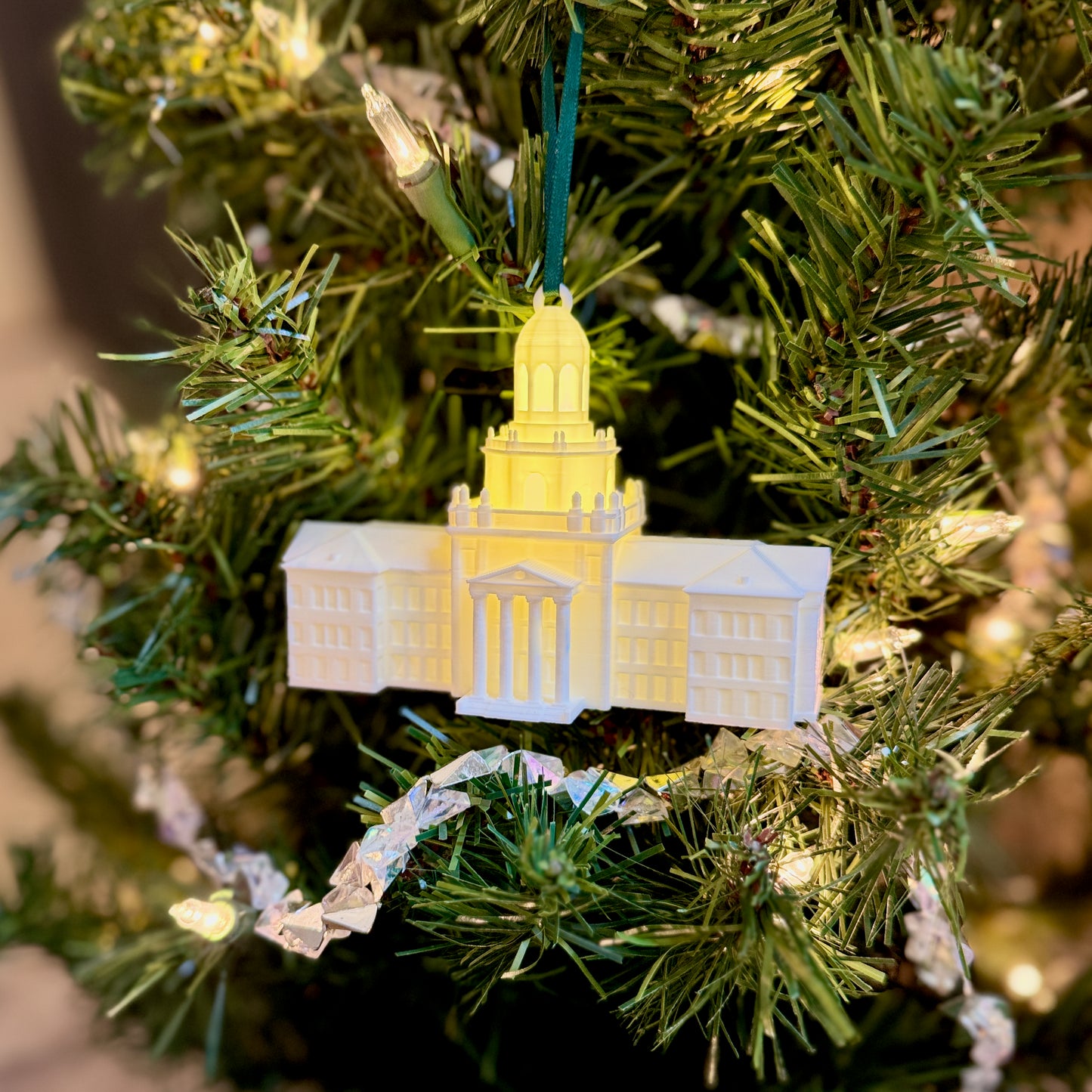 Angled perspective of a lighted Pat Neff Hall miniature, on a Christmas tree and showing the depth of the 3D-printed design.