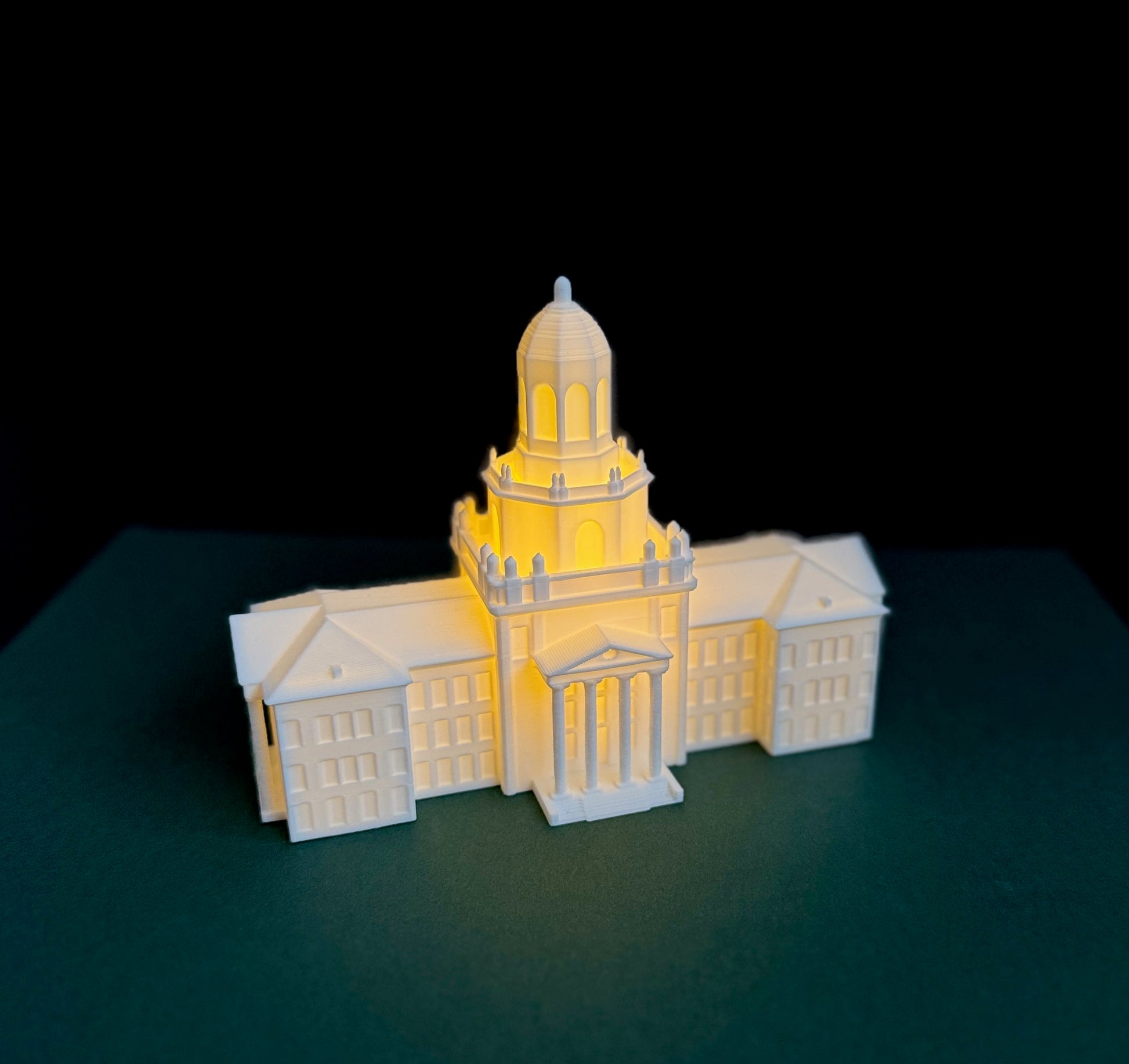 Warm LED lights shining through the tiny windows of a 3D printed Pat Neff Hall model used as a college party centerpiece.