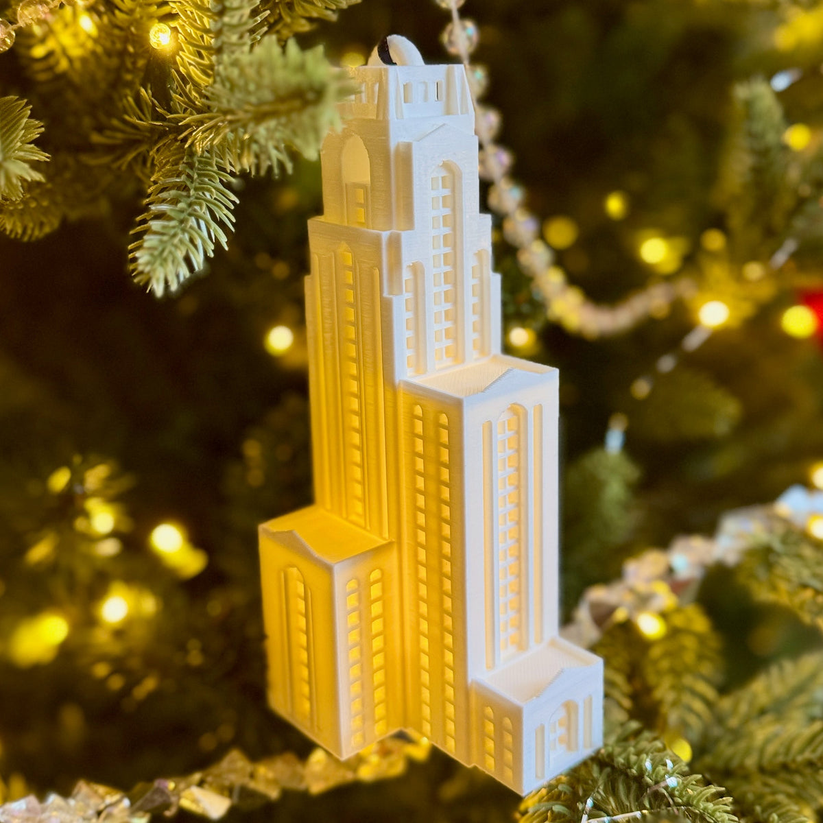 The Pitt Cathedral of Learning ornament with an LED light, shown on a Christmas tree.