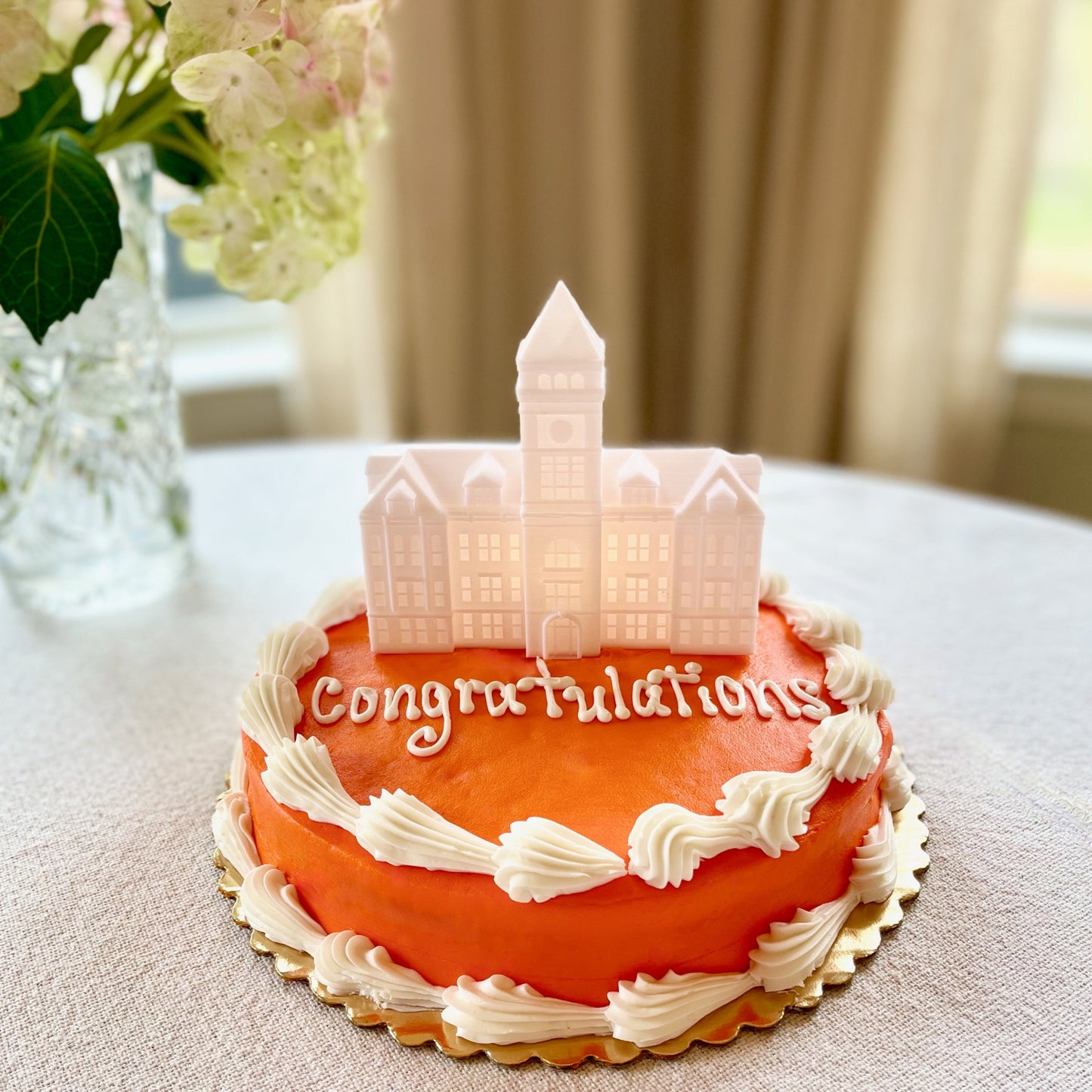 The Clemson graduation cake topper, shown on an orange cake.