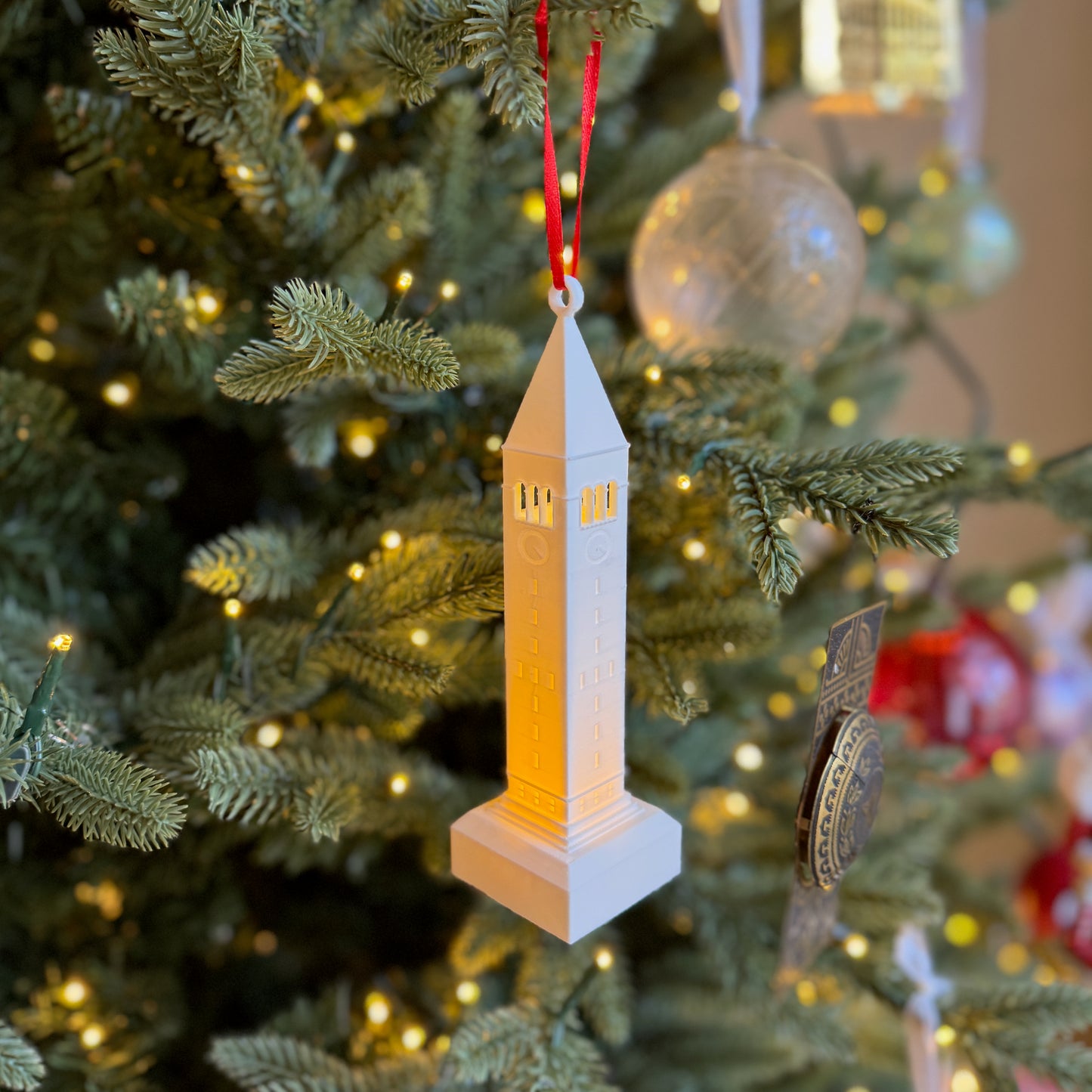The lighted Cornell ornament featuring McGraw Tower and shown on a Christmas tree.