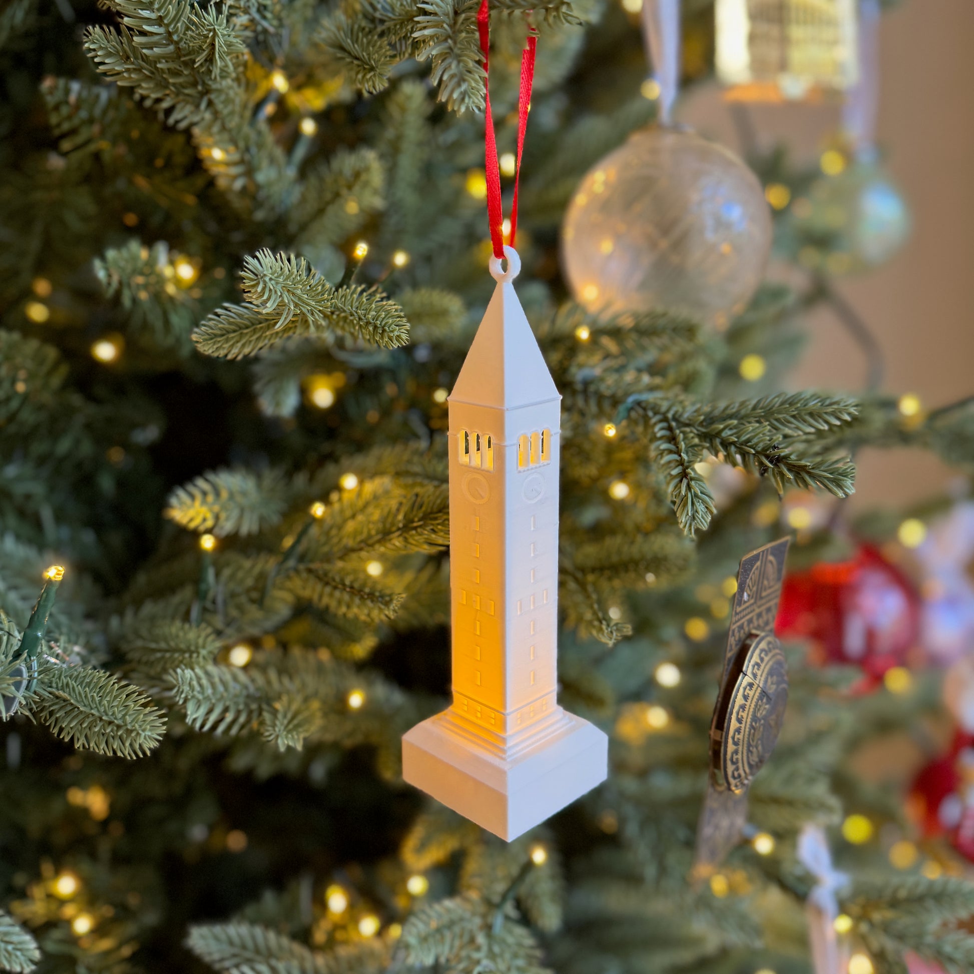 The lighted Cornell ornament featuring McGraw Tower and shown on a Christmas tree.