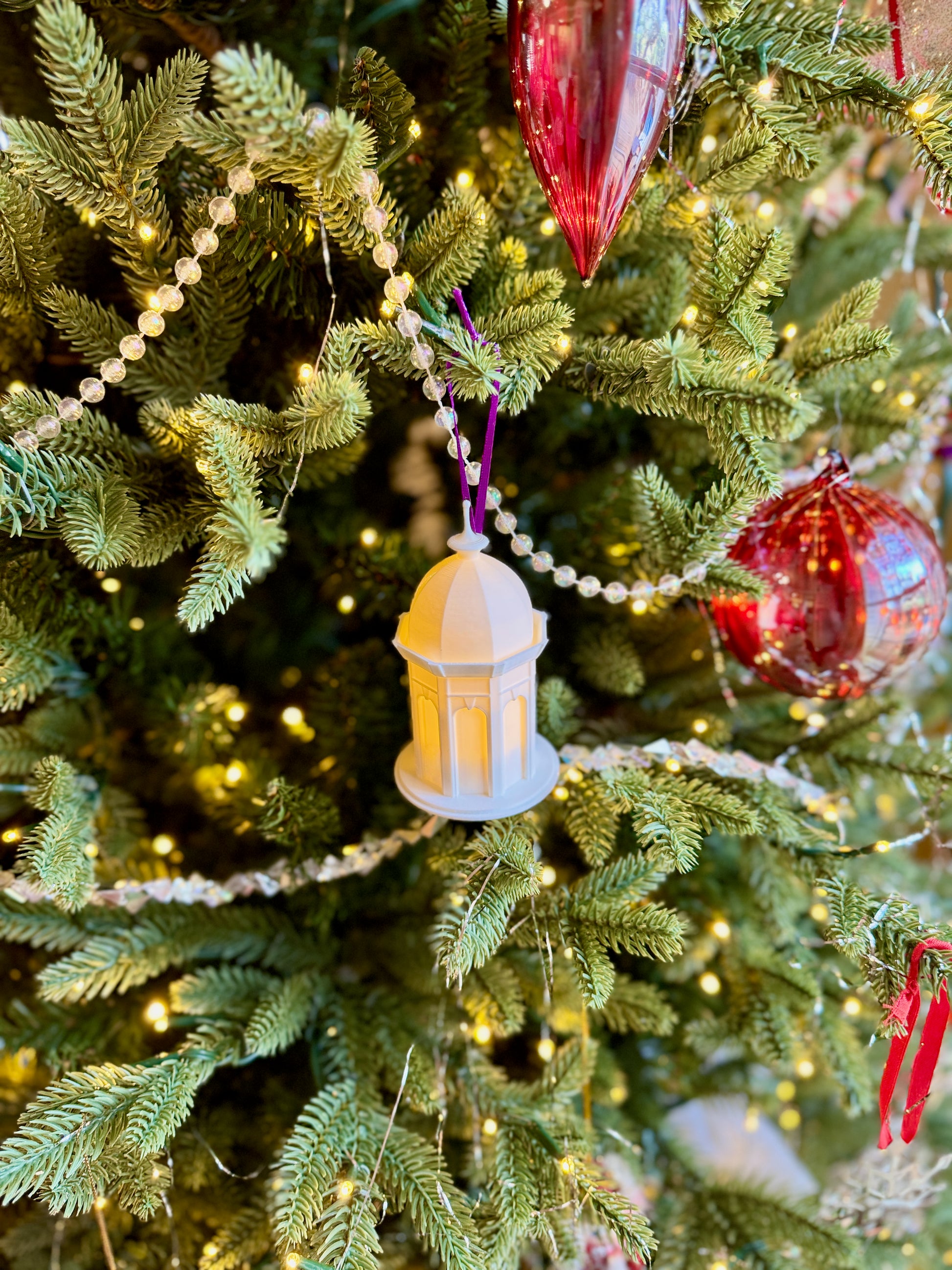 The ECU alumni ornament designed as the Cupola, shown with an LED light on a Christmas tree.