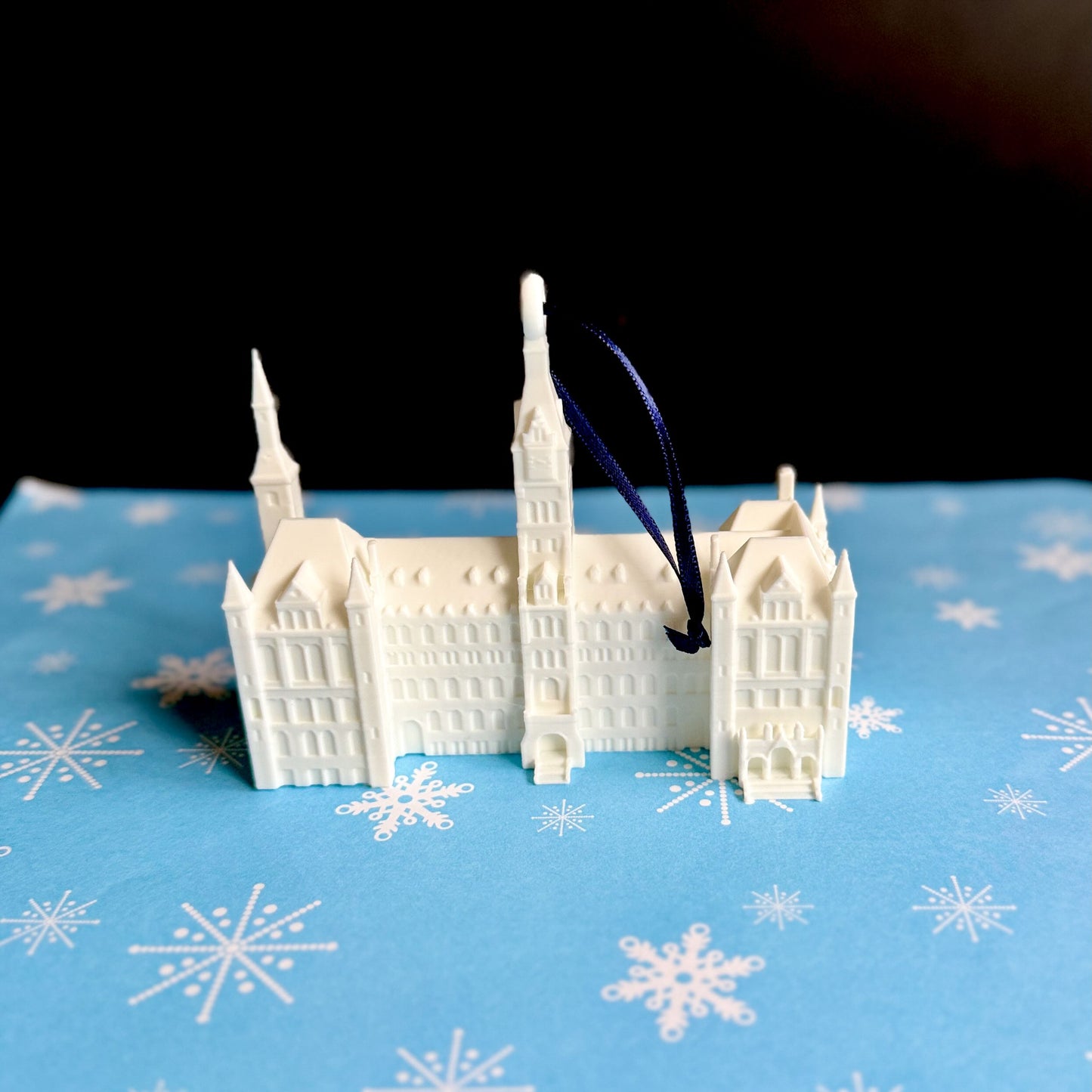 The Georgetown University ornament, shown against a blue holiday background and featuring Healy Hall.