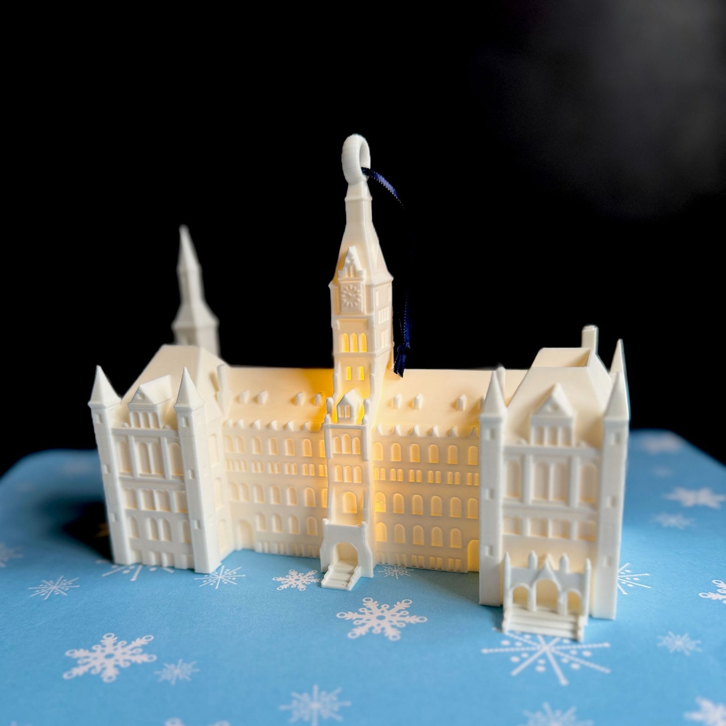 The lighted Georgetown ornament of Healy Hall, shown against a holiday background.
