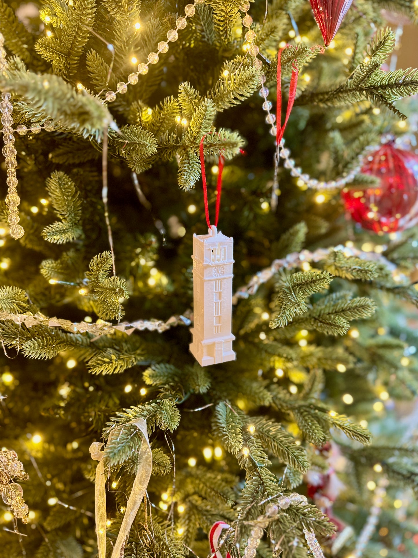 The NC State bell tower ornament, shown on a Wolfpack tree decorated for the holidays.