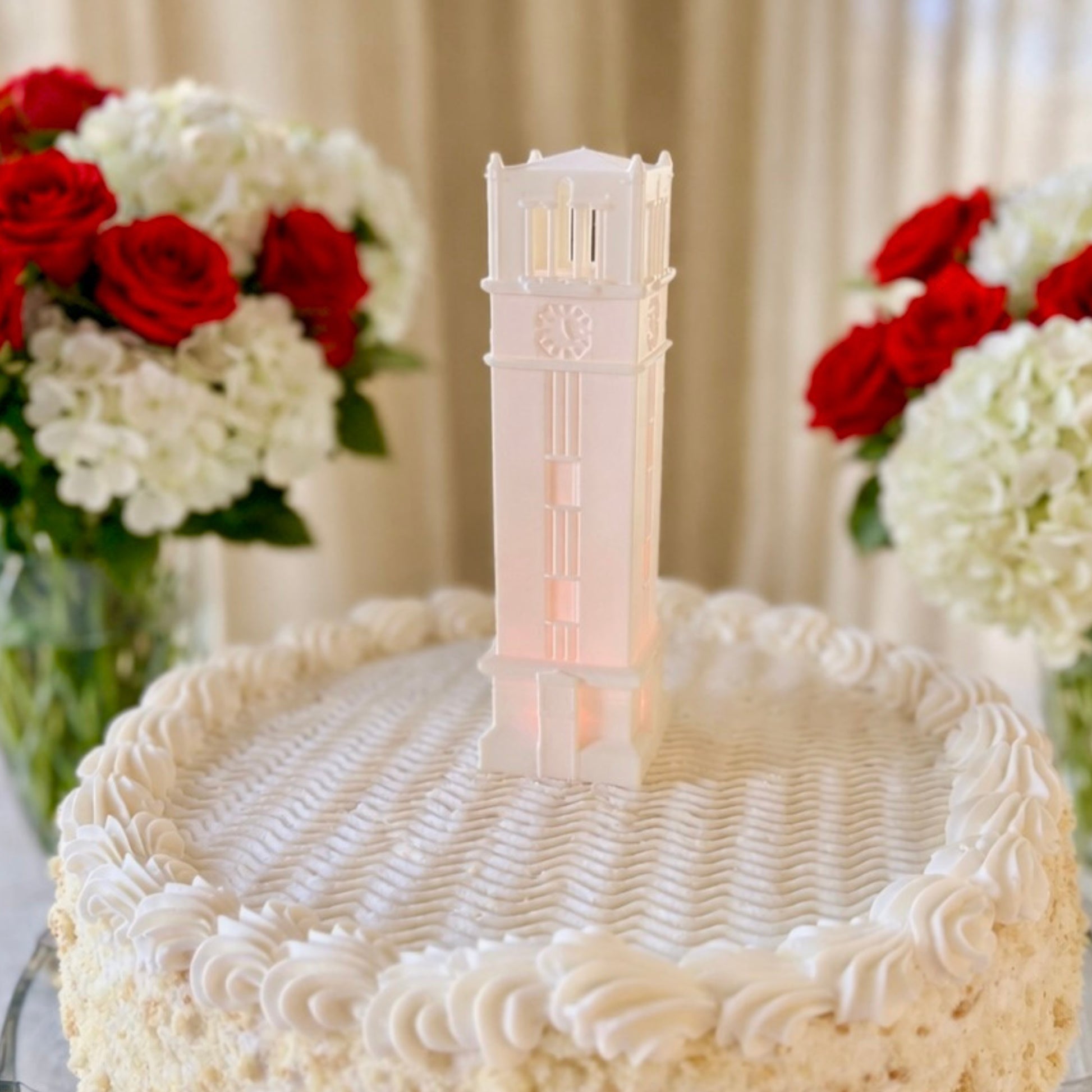 The NC State figurine representing the Memorial Bell Tower, with a red LED light and used as a cake topper on a graduation cake or a groom's cake.