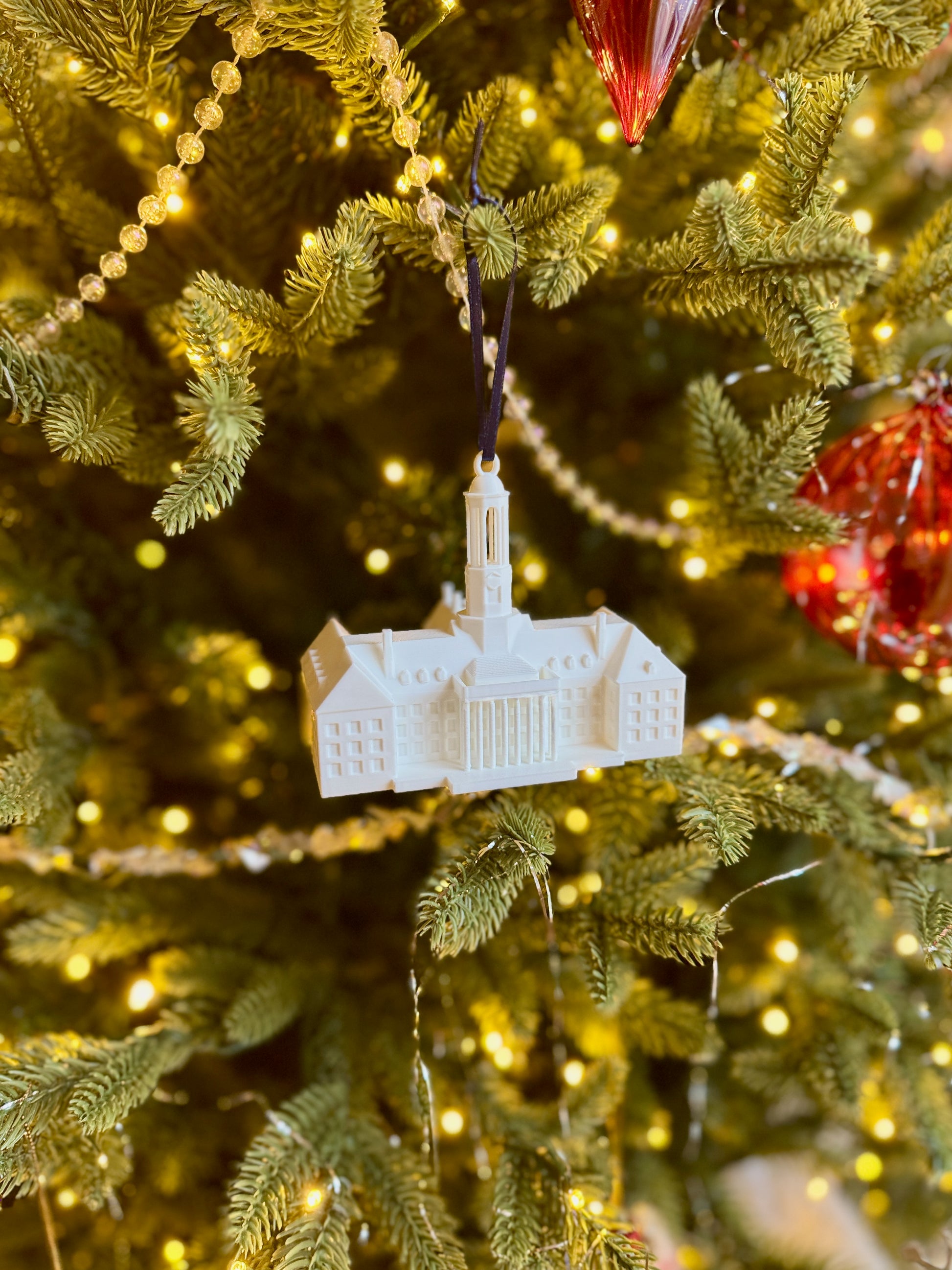The Penn State alumni ornament featuring the Old Main building and shown on a Christmas tree.
