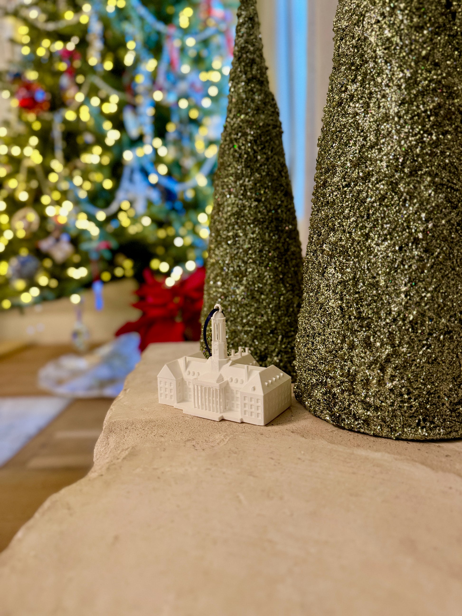 Small model of the Penn State Old Main building on a surface with Christmas decorations in the background