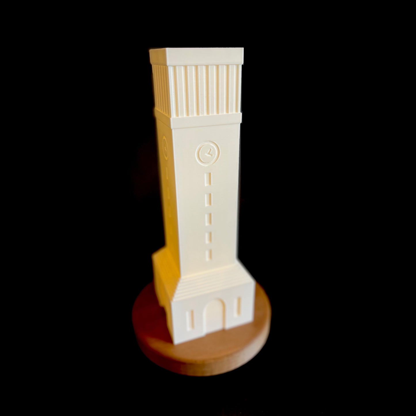 Illuminated white 3D printed Albritton Tower night light glowing warmly on a dark wooden base.