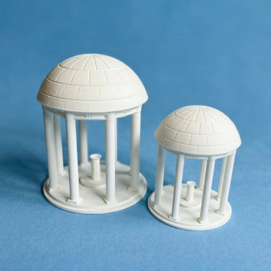 The UNC Old Well figurines, shown in detail against a Carolina Blue background.