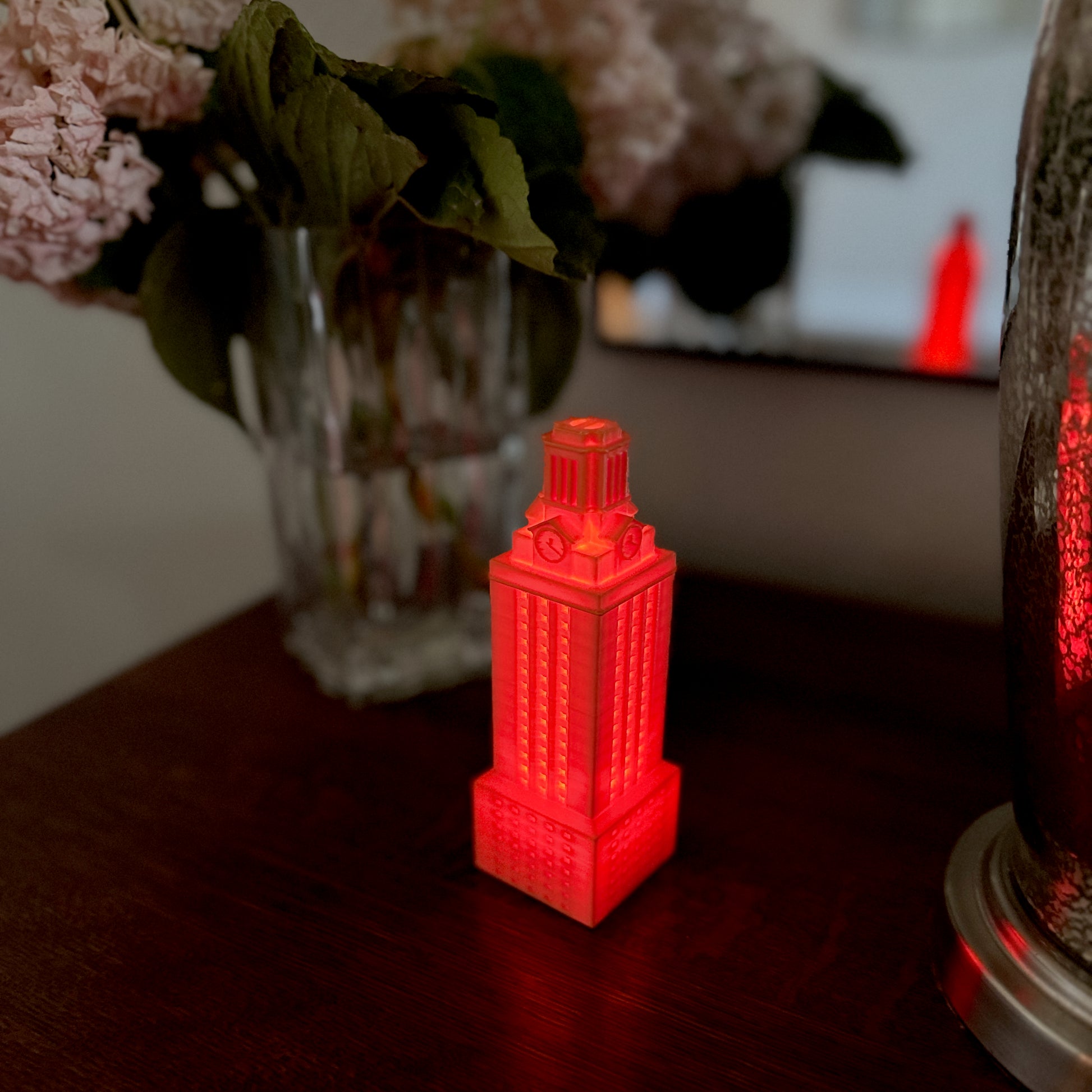 The lighted figurine of the UT Austin tower, shown on a bedroom side table and used as Texas Longhorns decor.