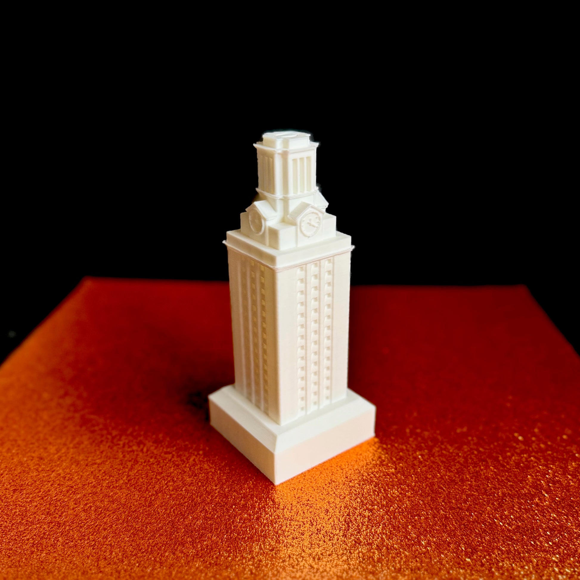 Detailed 3D printed UT Tower model displayed on a burnt orange textured background.