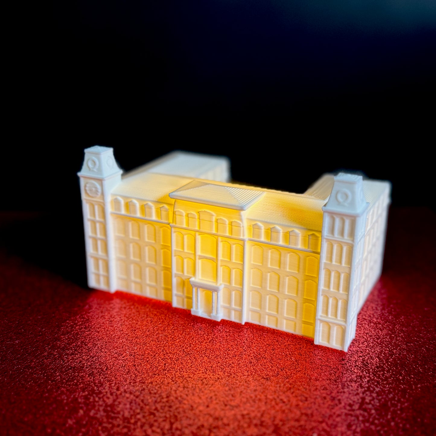 The University of Arkansas Old Main figurine, shown against a red background.