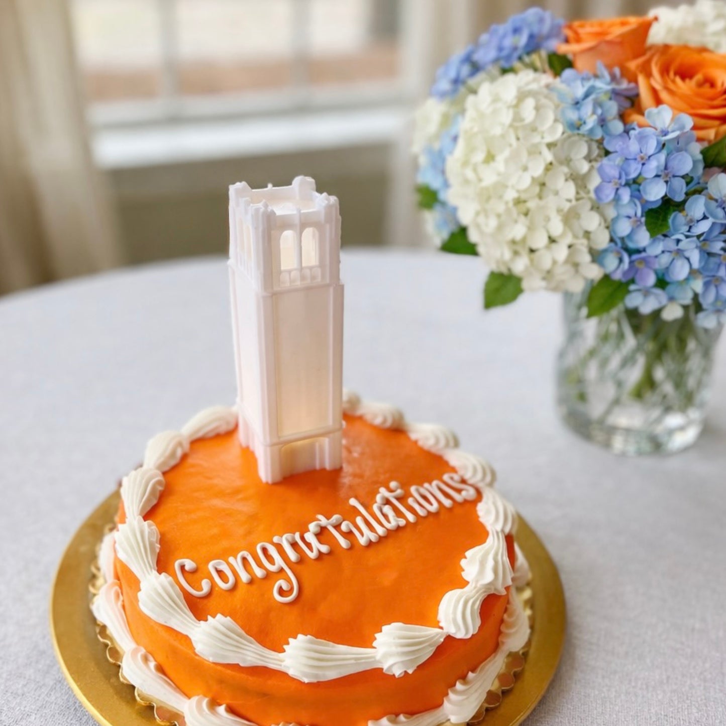 The Florida Gators cake topper light designed as the Century Tower building and shown on an orange graduation cake.