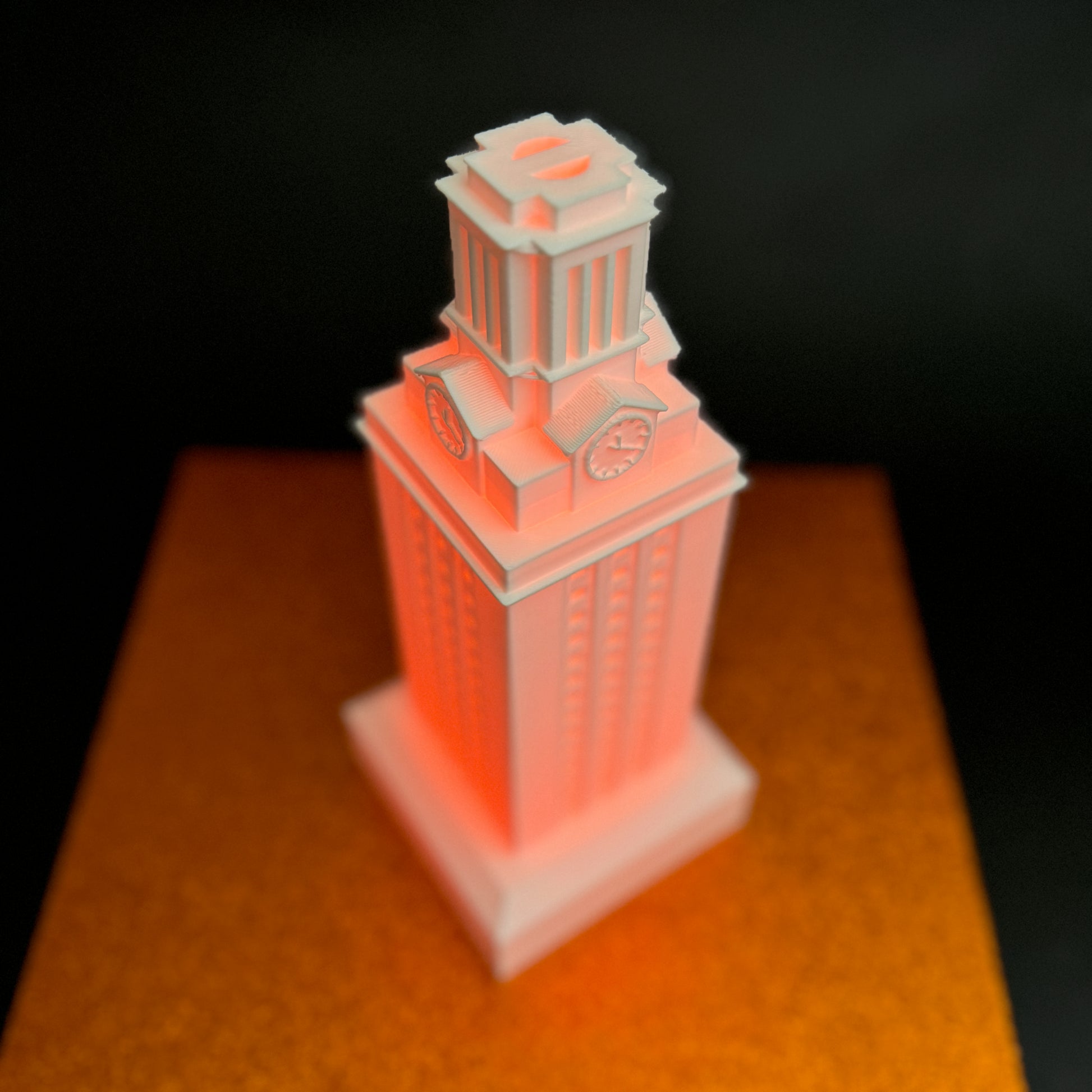 The University of Texas figurine of the UT Austin Tower, shown with an orange light.