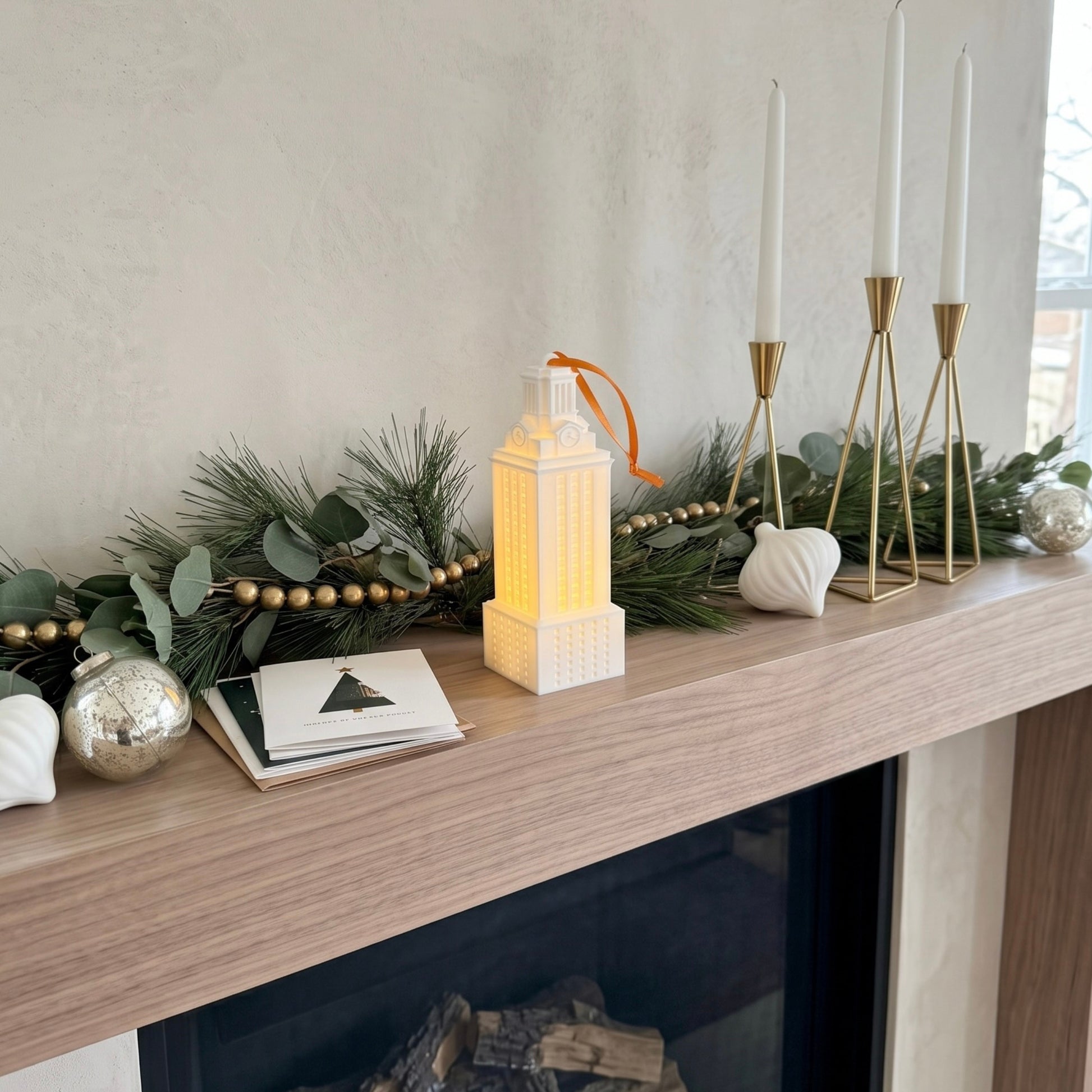A University of Texas ornament designed as the UT Tower and shown on the mantle of a home decorated for the holidays.