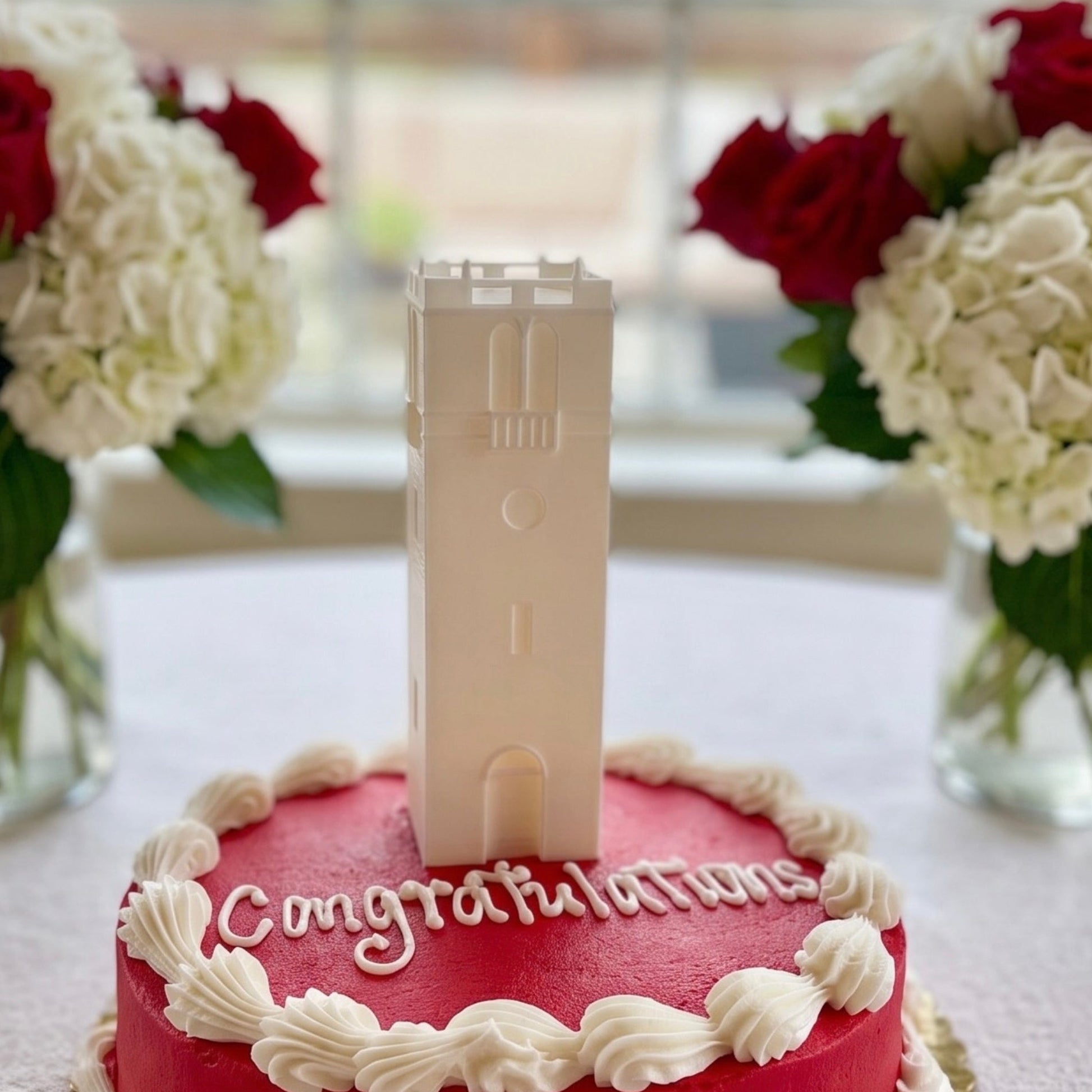 A University of Wisconsin cake topper, shown on a red graduation cake at a party.