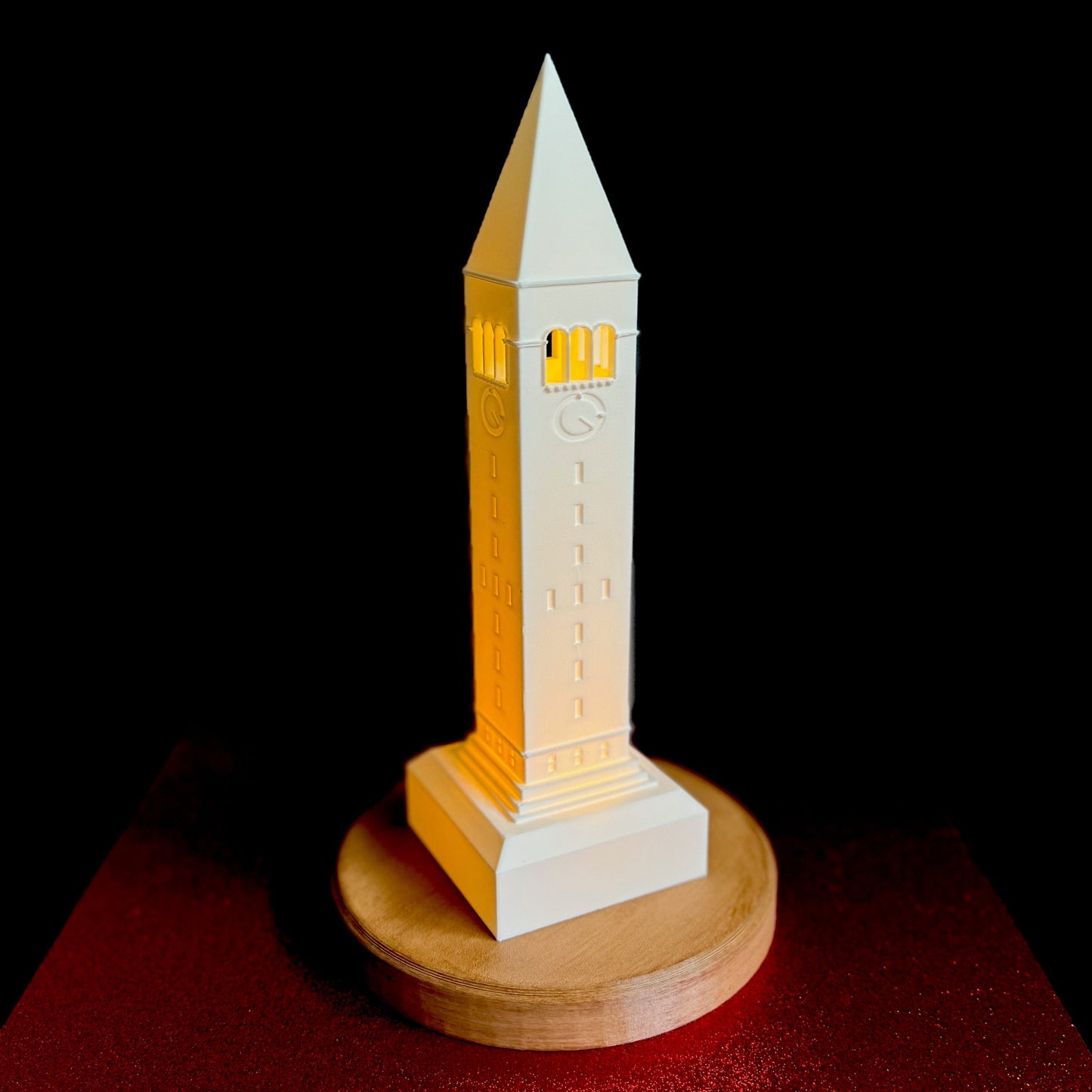 The Cornell lamp, shown against a red background and designed as a replica of the McGraw Tower campus building.